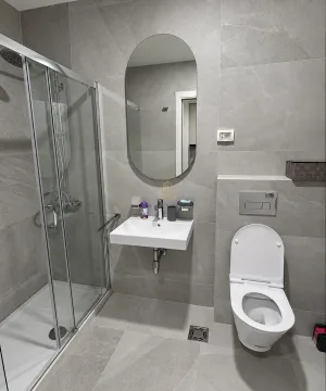 Modern bathroom equipped with a shower cabin, washbasin, and toilet. - image 5