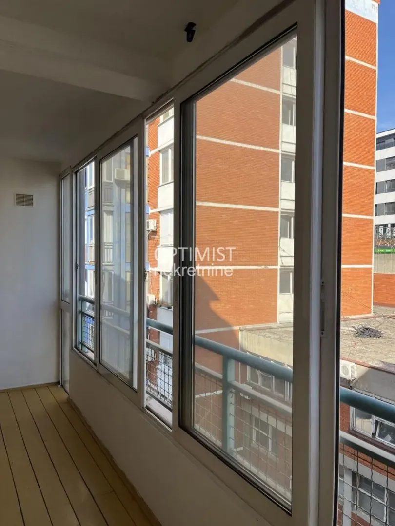 Zastakljeni balkon sa pogledom na susedne zgrade.