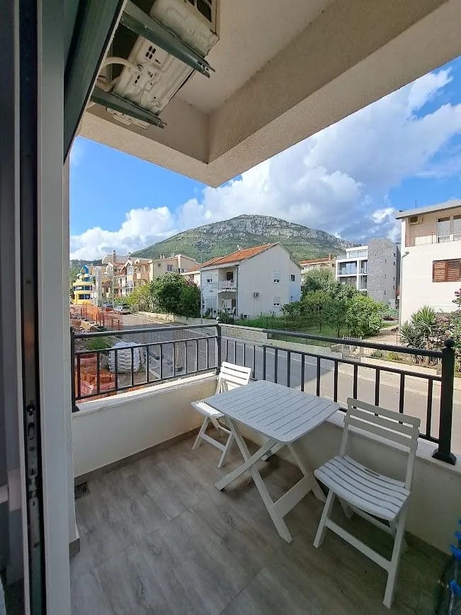 Manji namješten balkon sa stolom, stolicama i pogledom na okolinu.