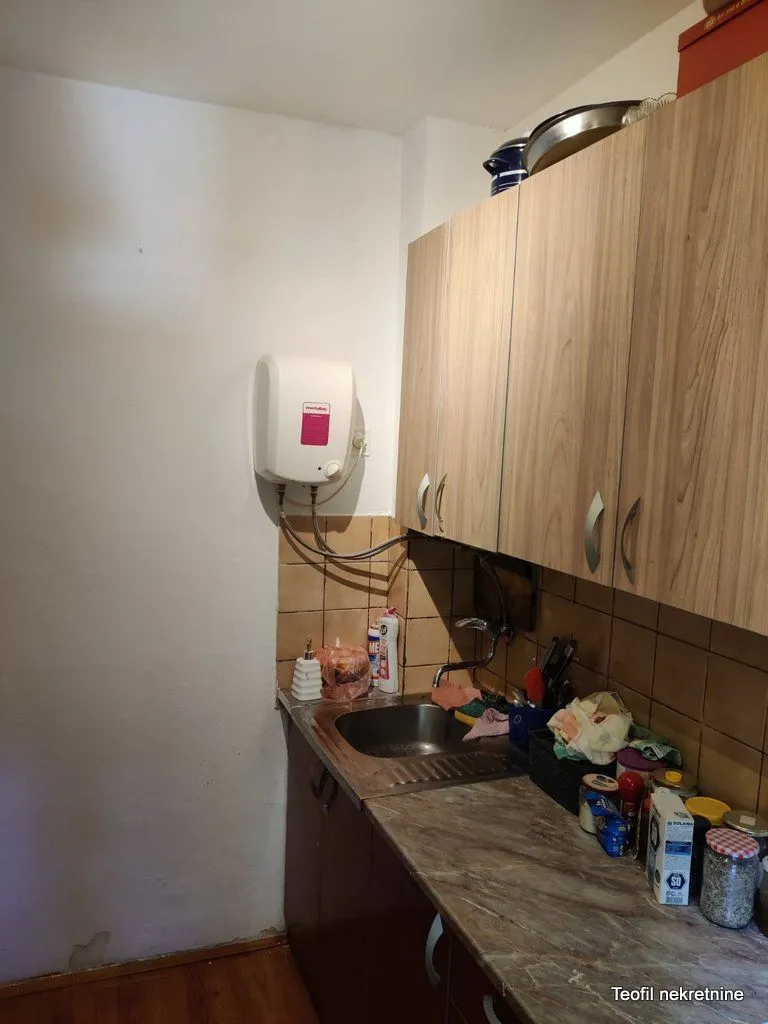 Manja kuhinja sa sudoperom, radnom površinom i zidnim elementima.