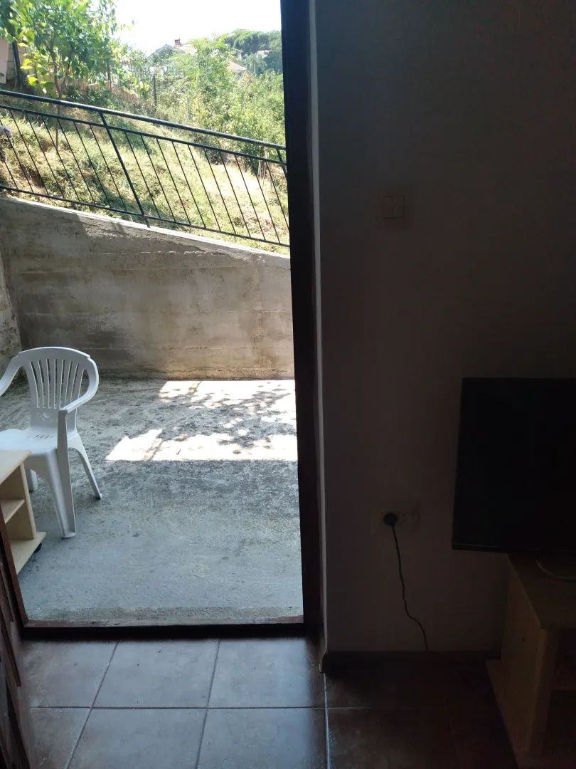 Pogled iz enterijera na spoljašnju terasu sa garniturom.