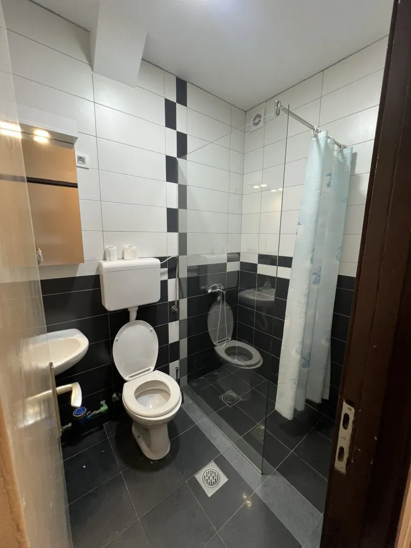 A simple bathroom with a walk-in shower and black and white tiles.