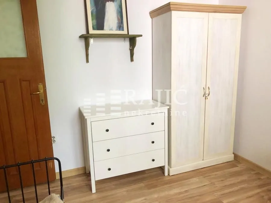 Bedroom with a white dresser, wardrobe, and wooden floor.