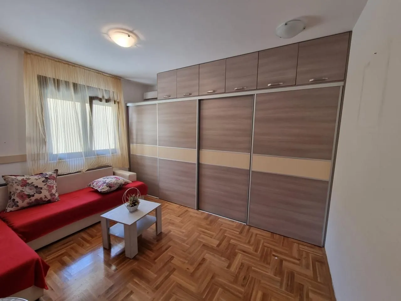 Dnevna soba sa garniturom, stočićem i velikim ugradnim plakarom.