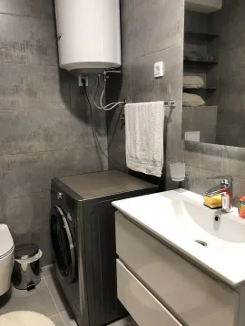 Modern bathroom with a sink, washing machine, and water heater. - image 22