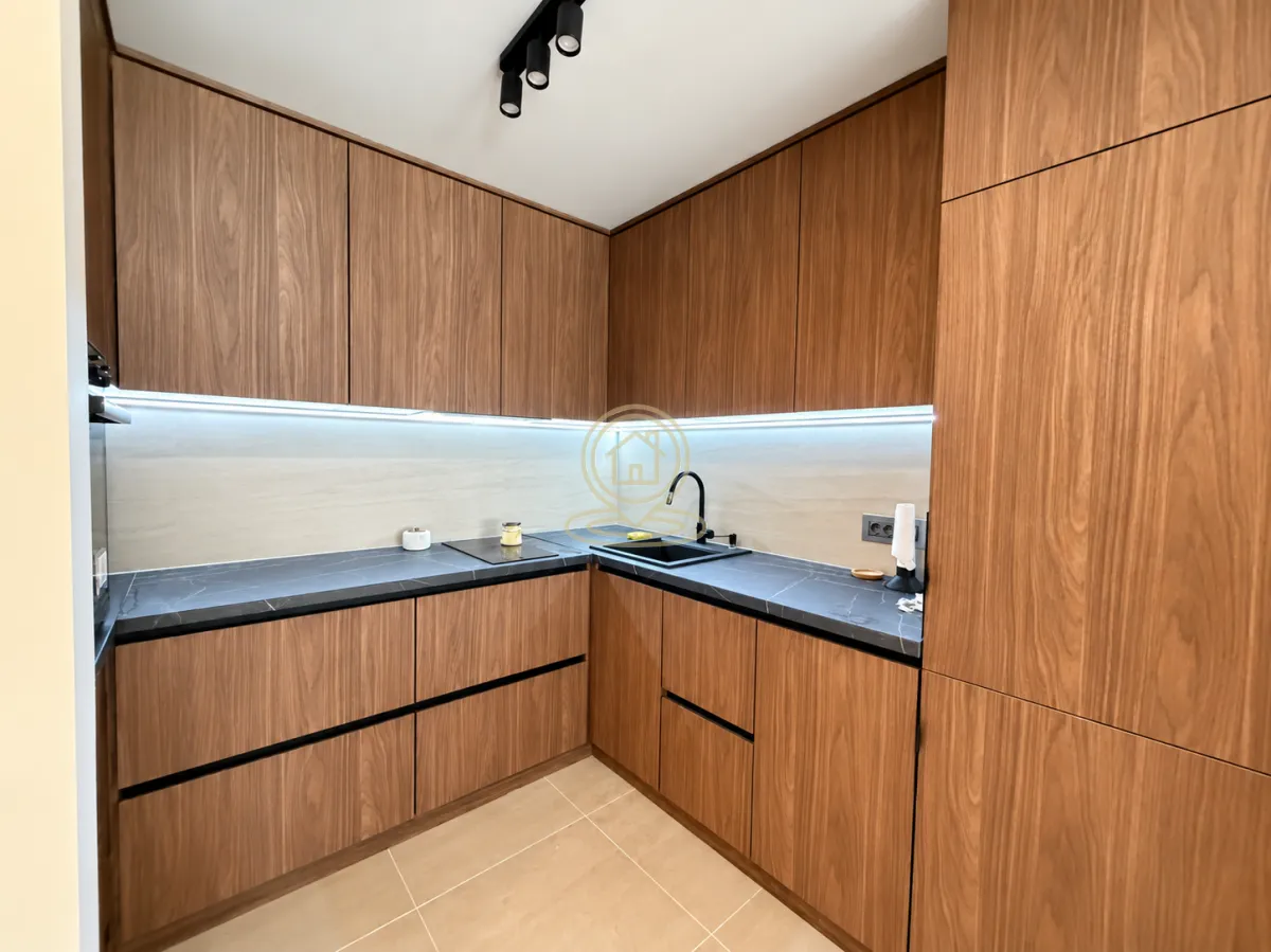 Modern kitchen with wooden cabinets and dark countertop.