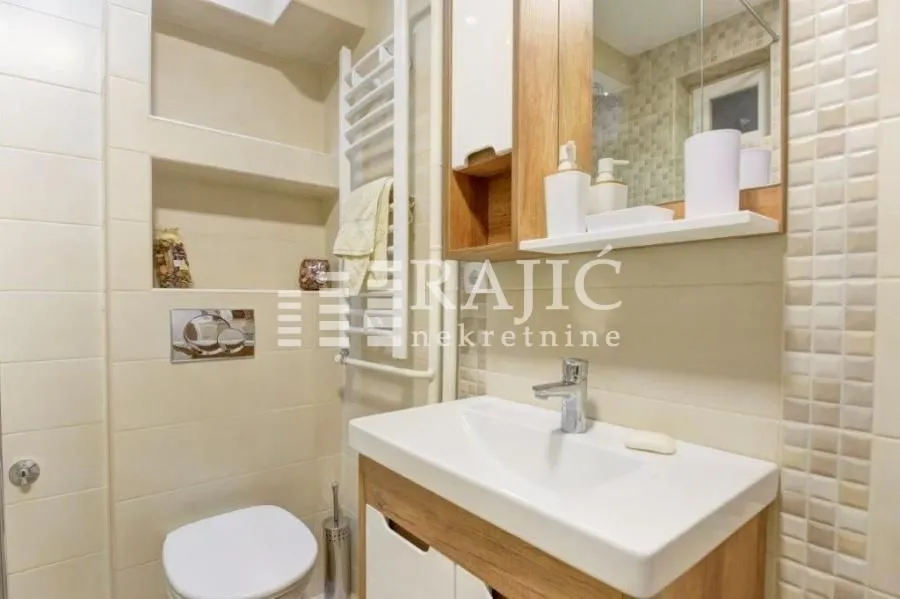 Small bathroom with a sink, toilet, and built-in shelving.