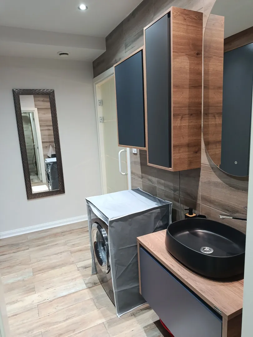 Modern bathroom with a washbasin, washing machine, and wall mirror.