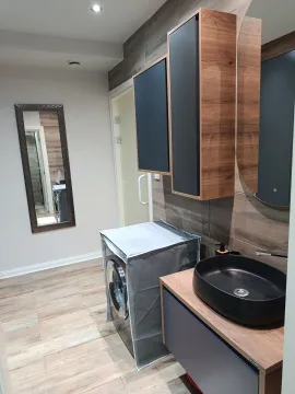 Modern bathroom with a washbasin, washing machine, and wall mirror. - image 11