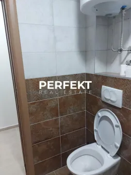 Smaller bathroom with a toilet and tiles in brown and white tones. - image 13