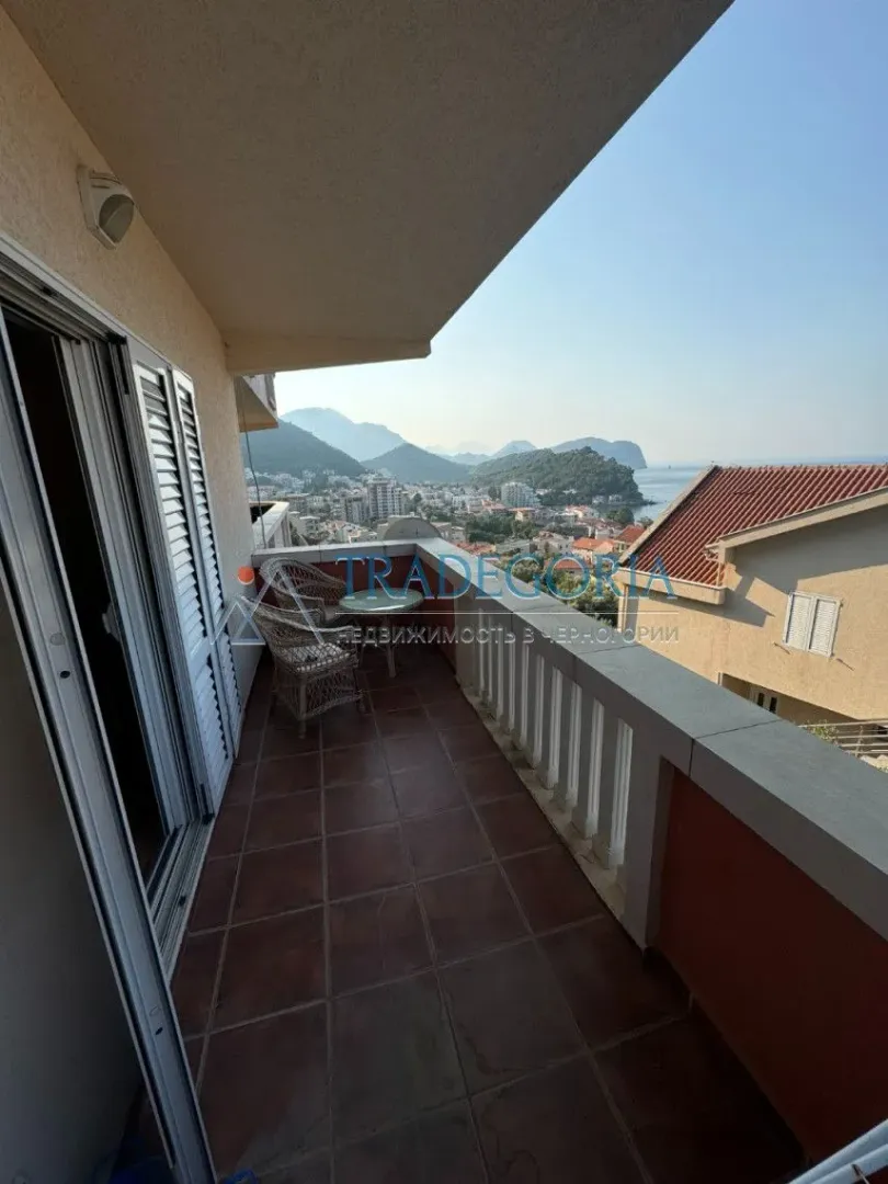 Natkriveni balkon sa garniturom za sjedenje i pogledom na grad i more.
