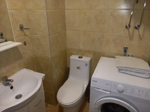 A simple bathroom with a washing machine, toilet, and sink. - image 8