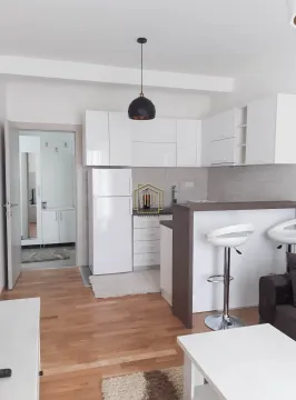Smaller white kitchen with a breakfast bar and bar stools integrated into the living area. - image 5