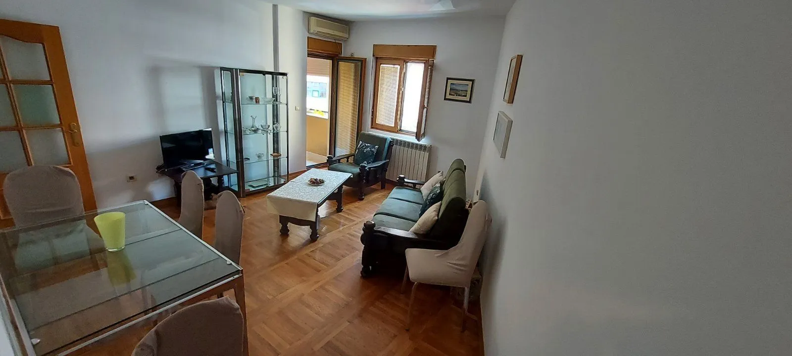 Svijetla dnevna soba sa trpezarijskim stolom i izlazom na balkon.
