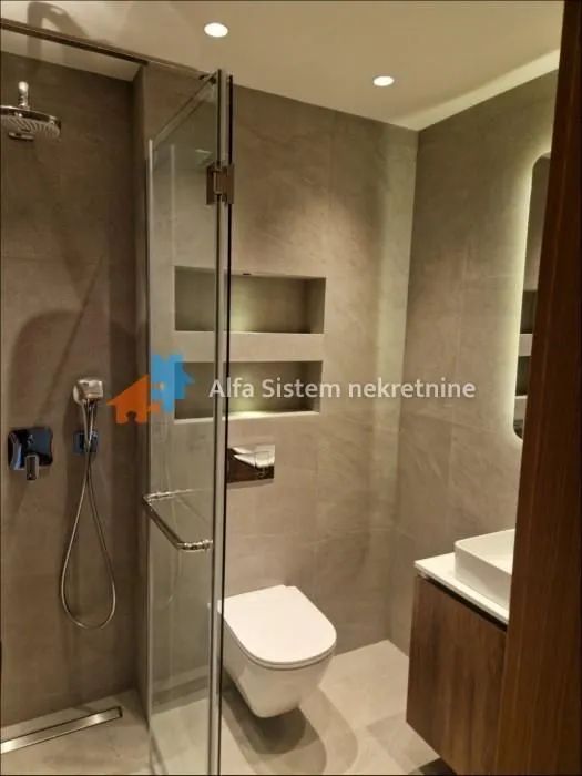 Modern bathroom with a walk-in shower, washbasin, and a wall-mounted toilet.