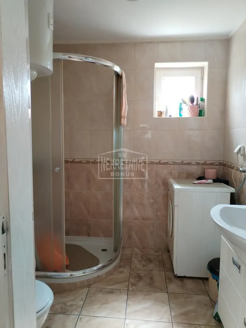Kupatilo sa tuš kabinom, umivaonikom i mašinom za veš.