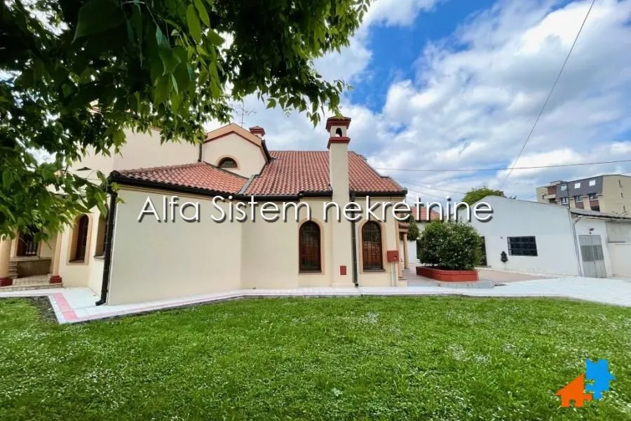 View of the exterior of the house with a manicured lawn and paved courtyard.