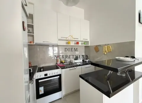 Moderna bijela kuhinja sa crnim radnim površinama i šankom. - image 5