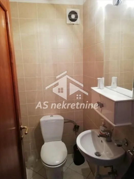 Smaller bathroom with a toilet, washbasin, and a mirror with a cabinet.