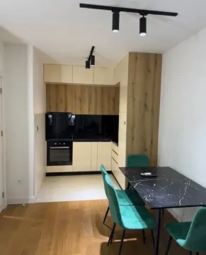 Moderna kuhinja sa trpezarijskim stolom i zelenim stolicama. - image 3