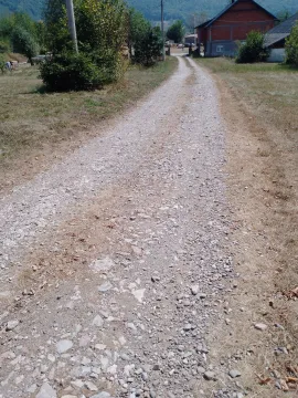 Prikaz makadamskog puta koji vodi prema imanju sa kućom u pozadini. - image 3