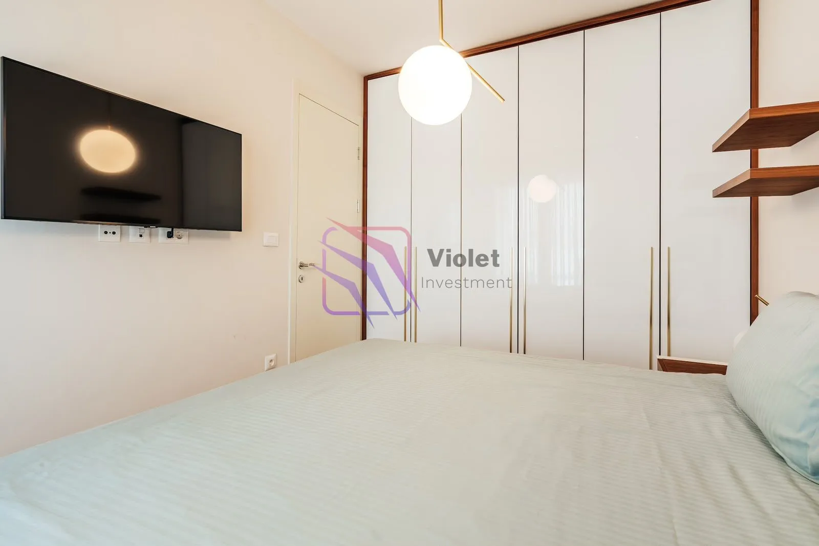 Modern bedroom with a double bed, built-in wardrobe and a wall-mounted TV.