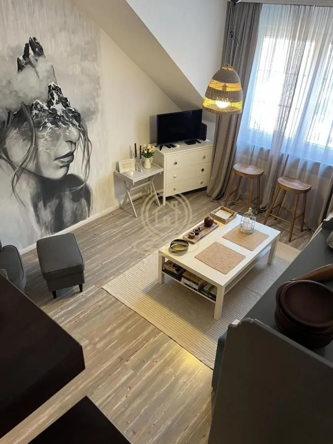 Dnevni boravak sa garniturom, stočićem i velikom umetničkom slikom na zidu.
