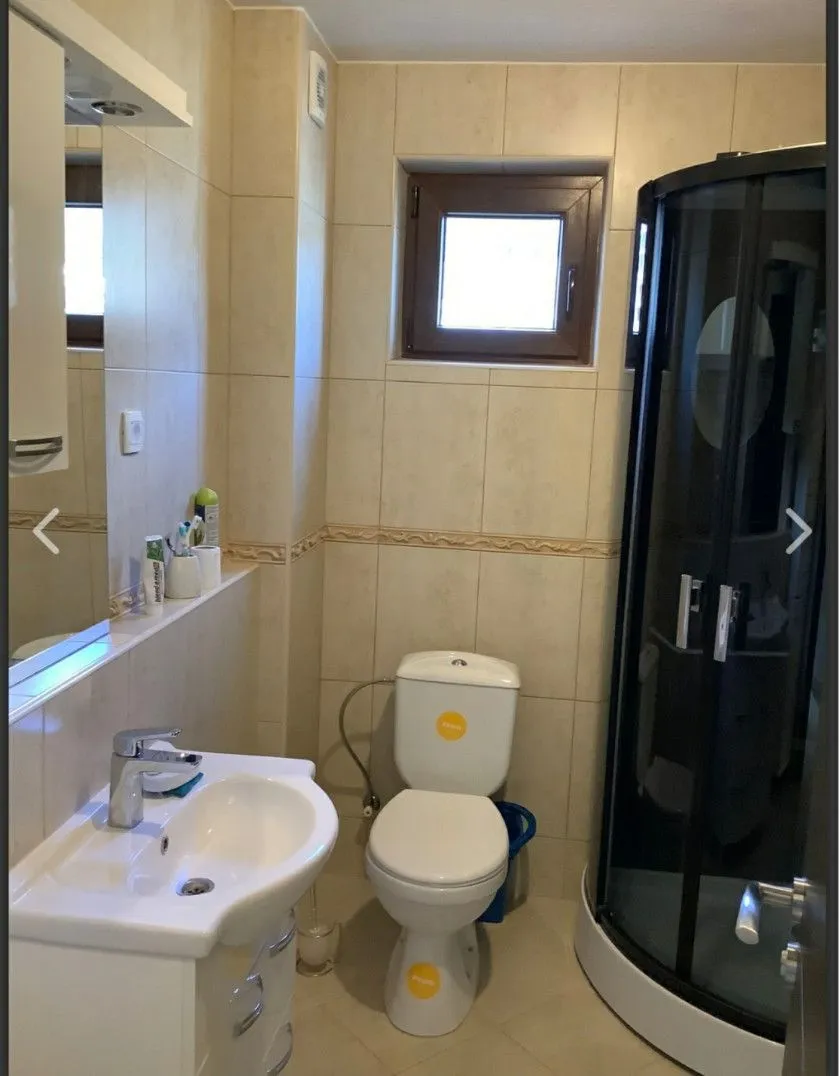 A compact bathroom equipped with a sink, toilet, and shower cabin.