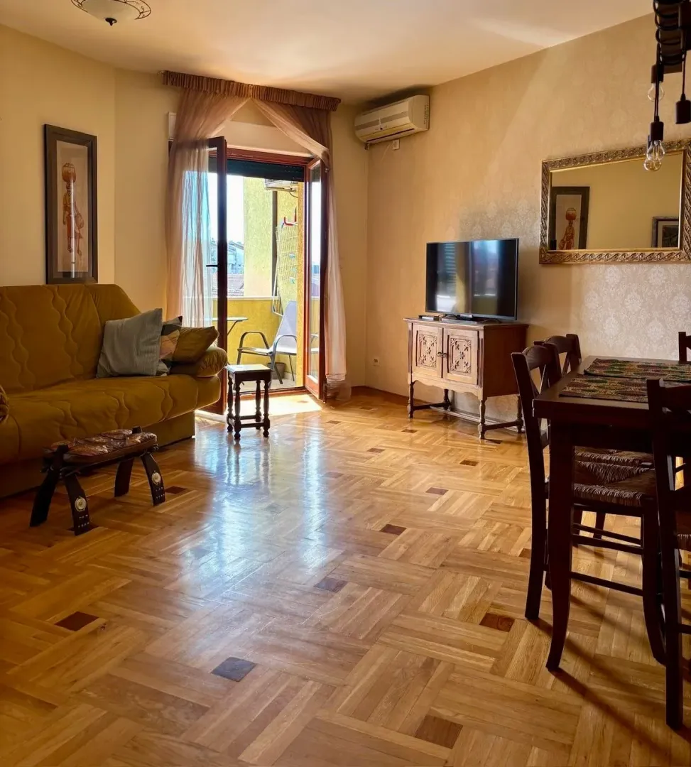 Living room with a sofa, dining table, and balcony access.
