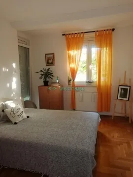 Nameštena spavaća soba sa bračnim krevetom, ormarom i narandžastim zavesama. - image 5