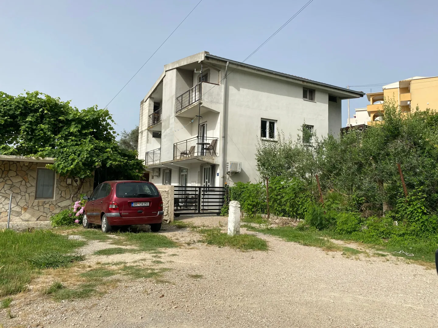 Exterior view of the house with a yard and a parked car.