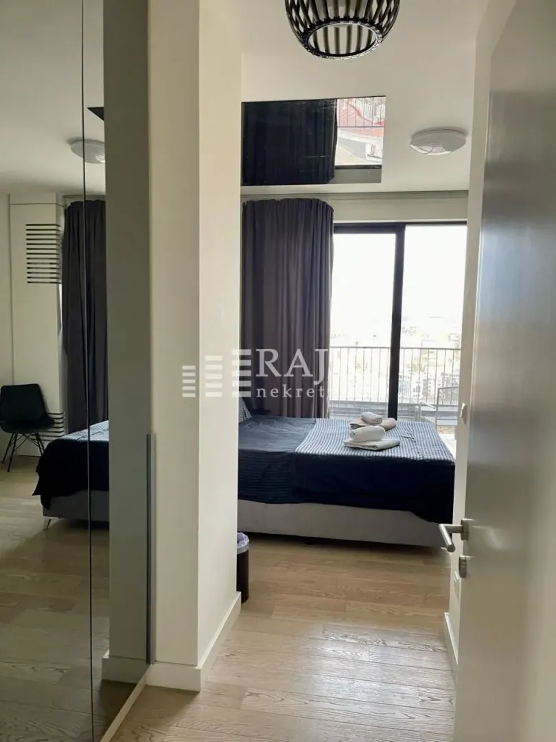 View from the hallway into a furnished bedroom with a double bed and access to the terrace.