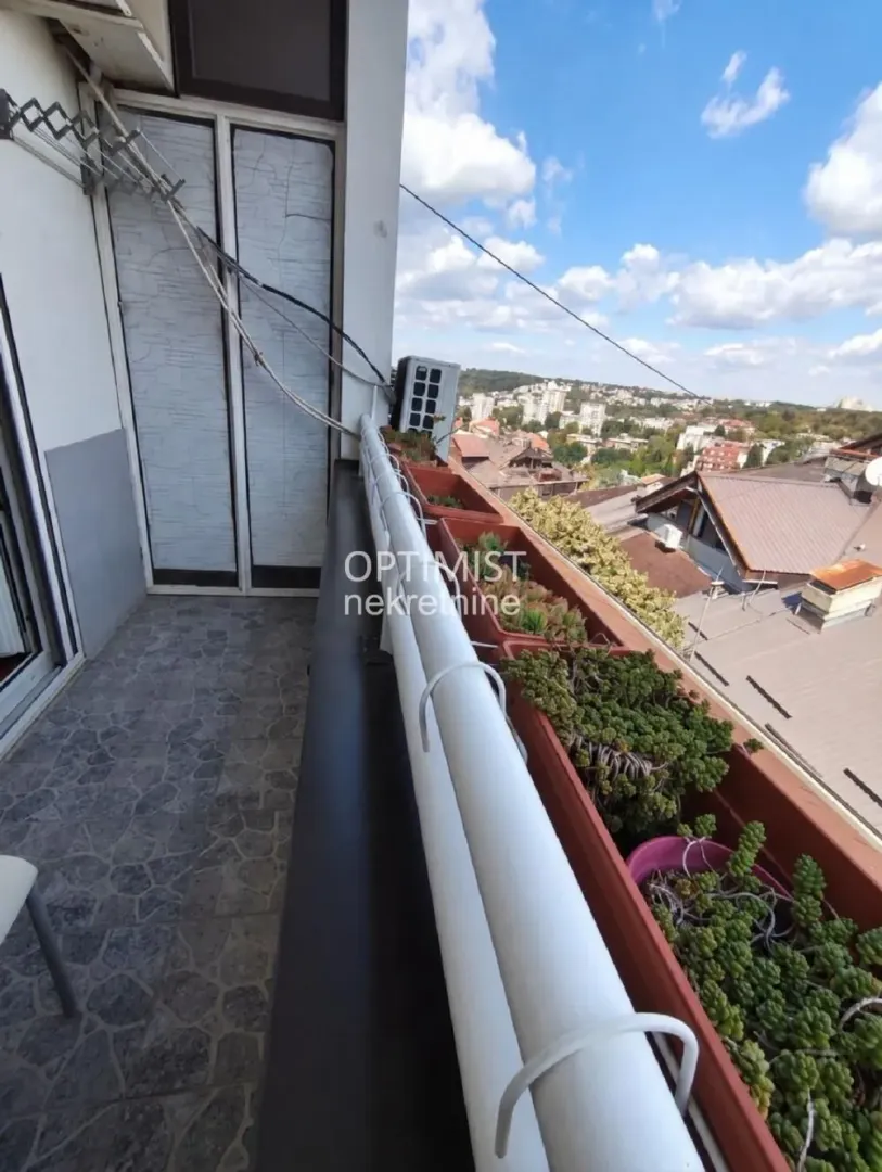 Manji balkon sa saksijama cveća i pogledom na grad.