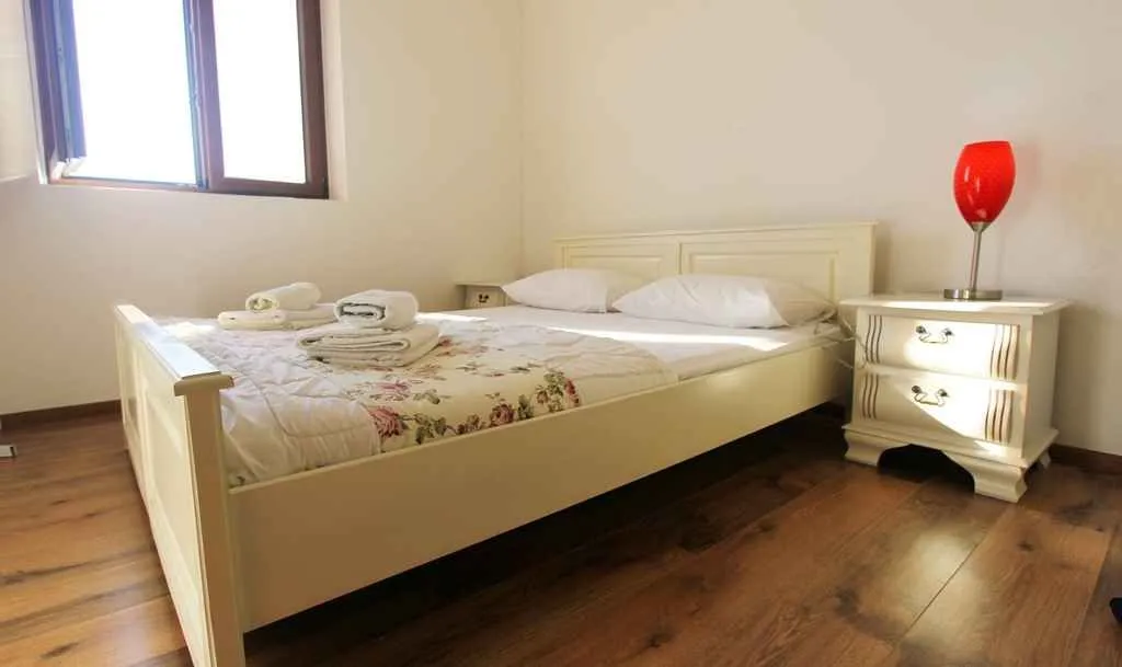 Namještena spavaća soba sa bračnim krevetom i noćnim stočićem.