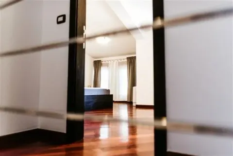 Bright bedroom with wooden flooring, viewed through a doorway. - image 17