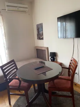 Dnevna soba sa okruglim trpezarijskim stolom, stolicama i televizorom na zidu. - image 8