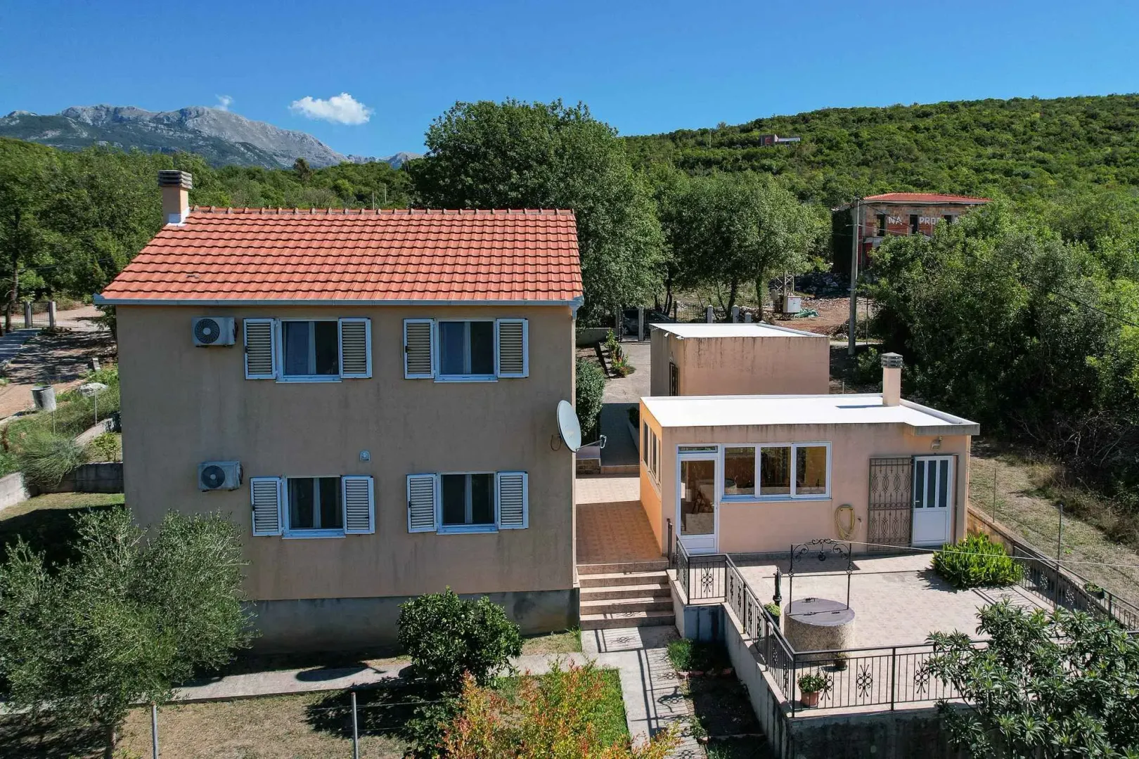 Pogled iz vazduha na kuću sa dvoriijem i pomoćnim objektima u prirodnom okruženju.