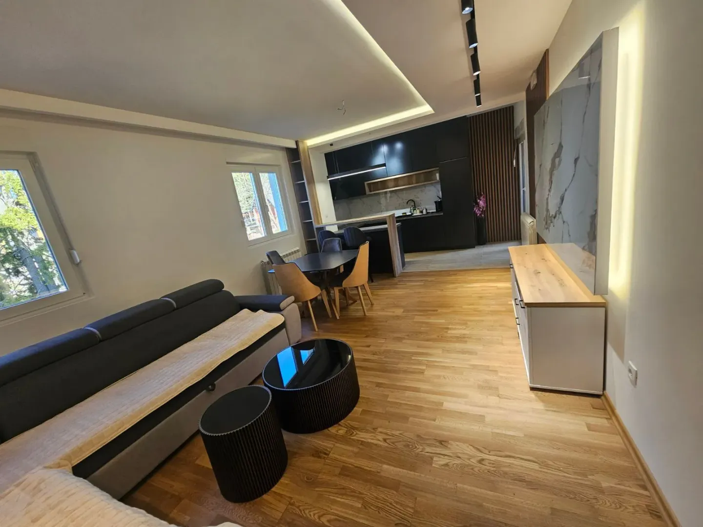 Moderan dnevni boravak sa garniturom i trpezarijom u nastavku.