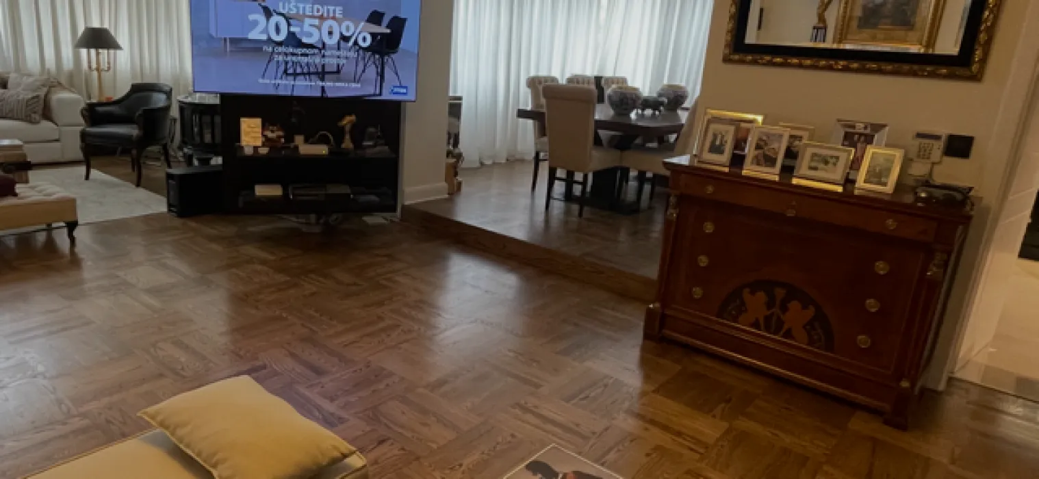 Prostrani dnevni boravak sa parketom i trpezarijom u pozadini.