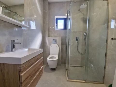 Modern bathroom equipped with a shower cabin, washbasin, and toilet. - image 10