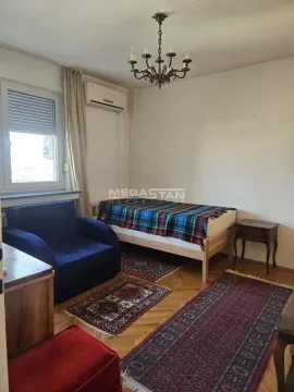Nameštena spavaća soba sa krevetom, foteljom i prozorom. - image 3