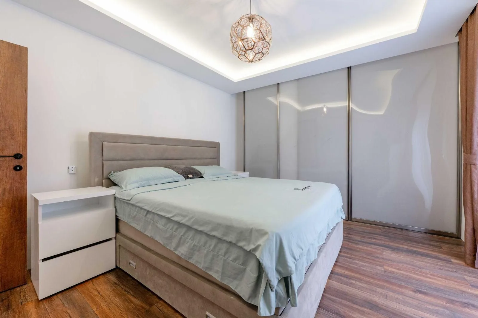 Moderna spavaća soba sa bračnim krevetom, ugradnim plakarom i spuštenim plafonom.