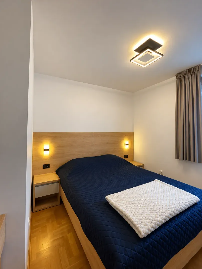 Modern bedroom with a double bed, wooden headboard, and bedside tables.