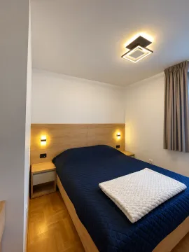 Modern bedroom with a double bed, wooden headboard, and bedside tables. - image 6