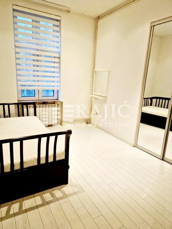 Bright bedroom with a bed and a large mirrored wardrobe.