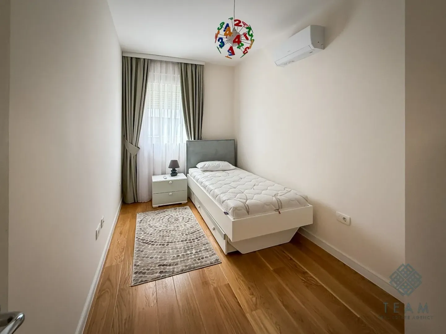 Small bedroom with a single bed, nightstand, and a window with curtains.