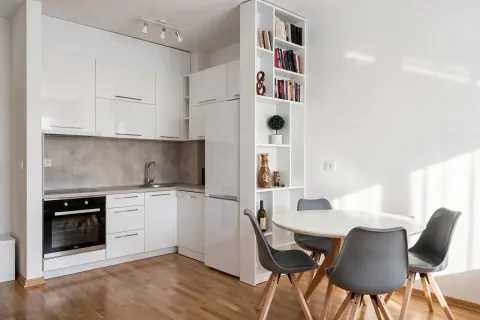 Modern white kitchen with a dining area and built-in shelving. - image 5