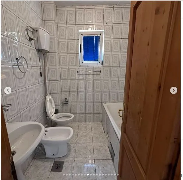 Kupatilo sa pločicama, kadom, bideom i prozorom.