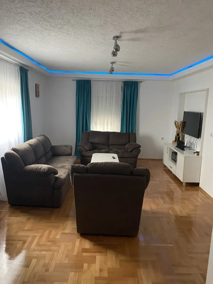 Living room with dark sofas and blue LED ceiling lighting.