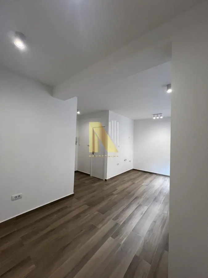 Empty room with light-colored walls and wooden flooring.